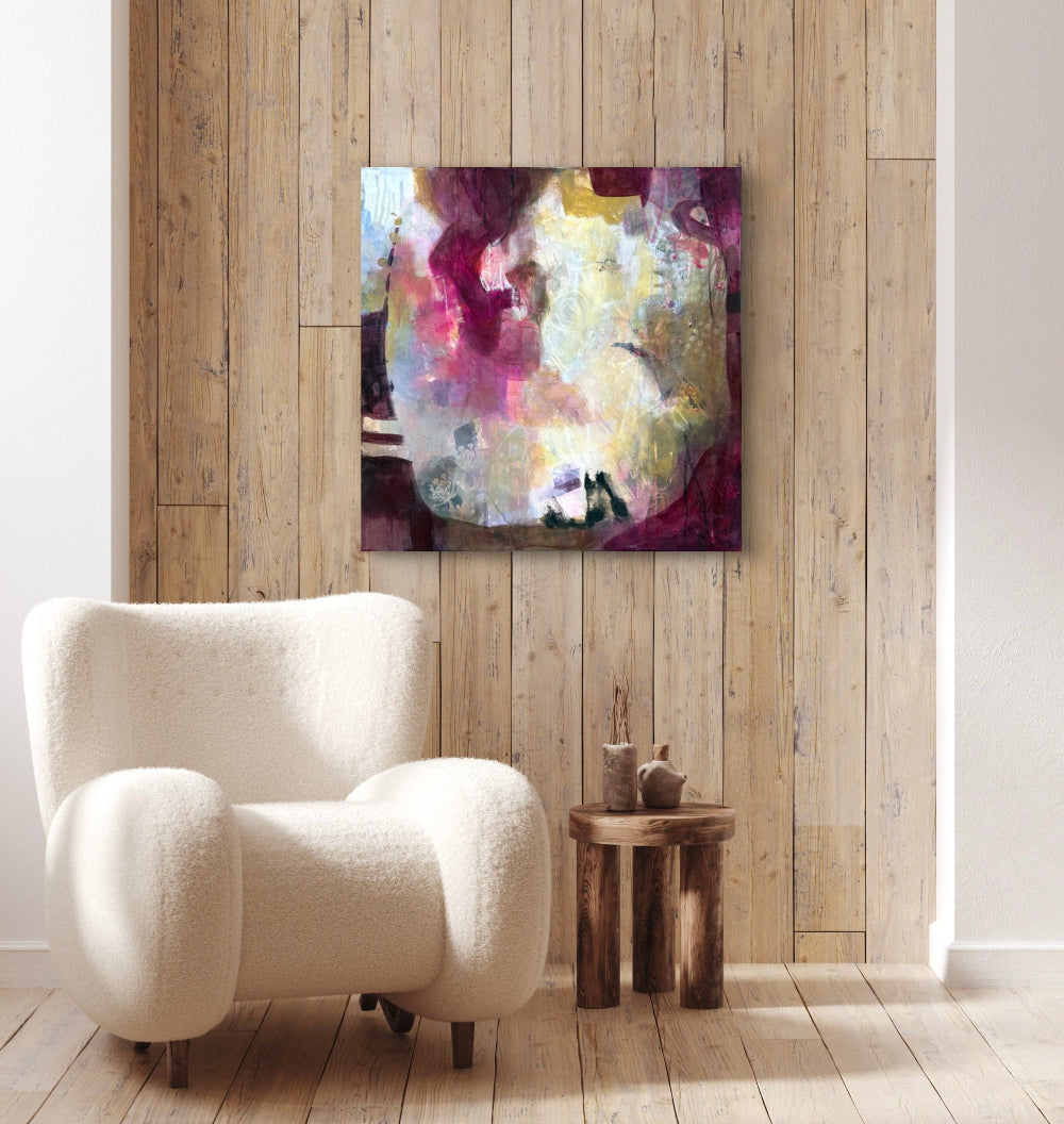 Showing the painting "Wine and Roses" as it would look on a wall above a chair and side table.