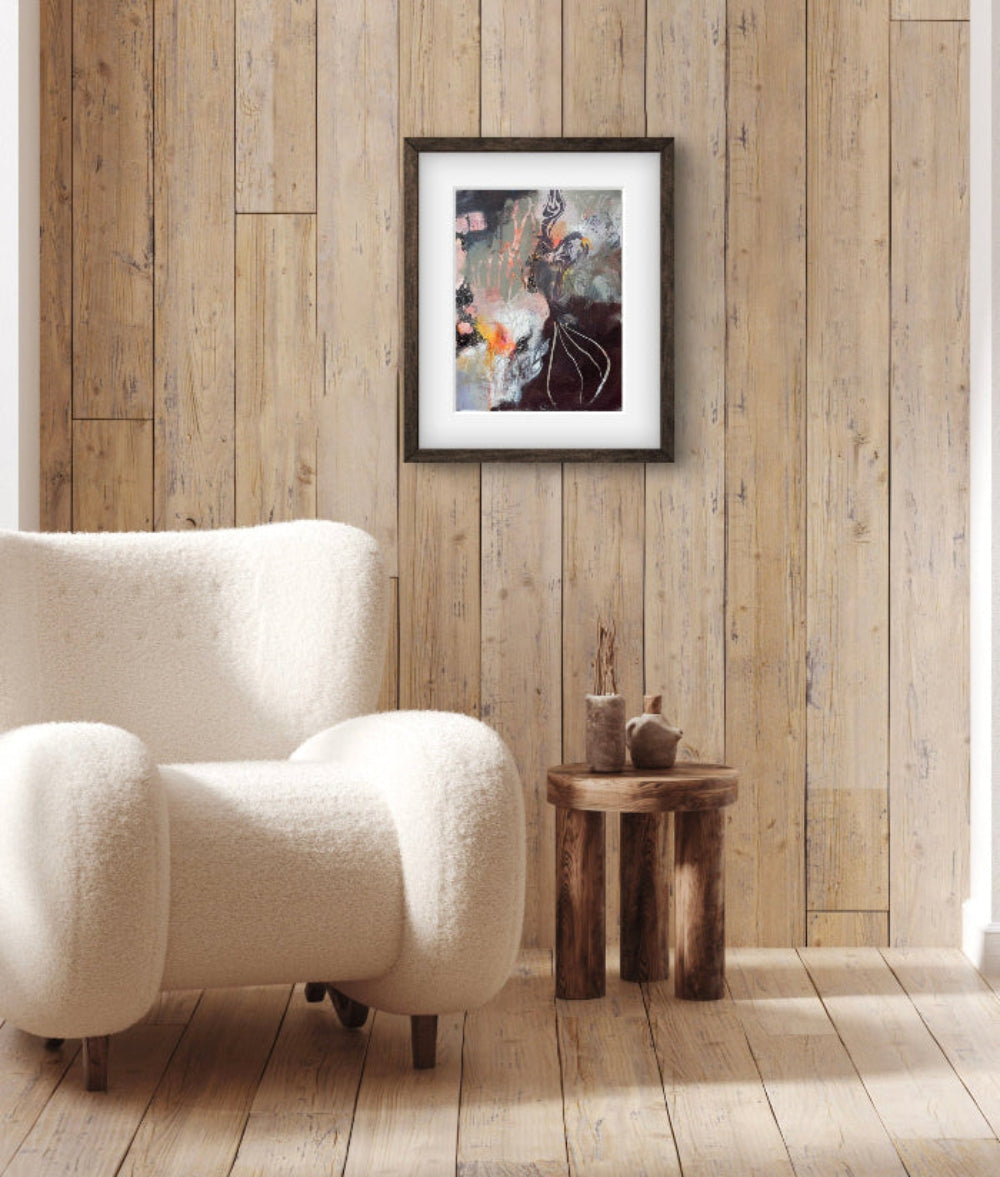 Demonstrates how the painting "Smells Like Chocolate" looks framed and hanging on a wall above a chair and side table.